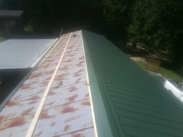 Old rusted panels beside newly installed green metal roofing — Wind Damage Roof Repair by Roofing Brothers in Warner Springs
