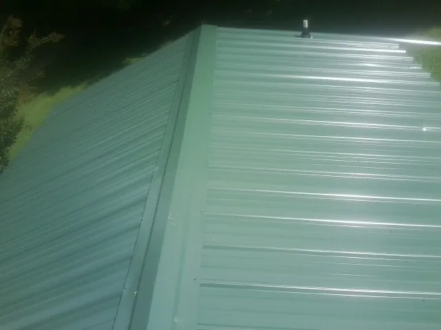 New green metal panels meeting at the ridge of a roof — Flat Roof Repair work by our crew in Warner Springs