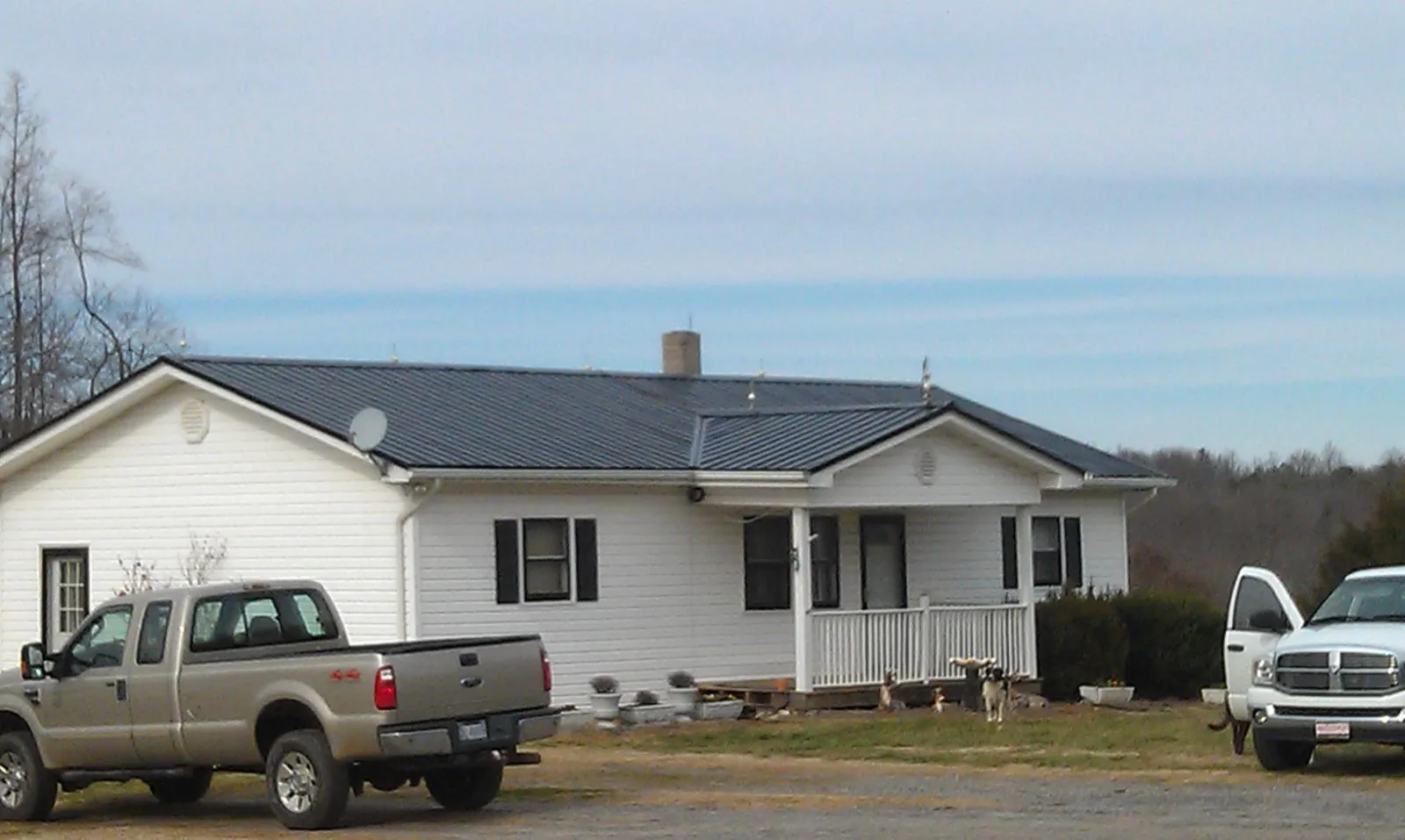 Finished dark metal roof on a white ranch home with work trucks parked in Warner Springs
