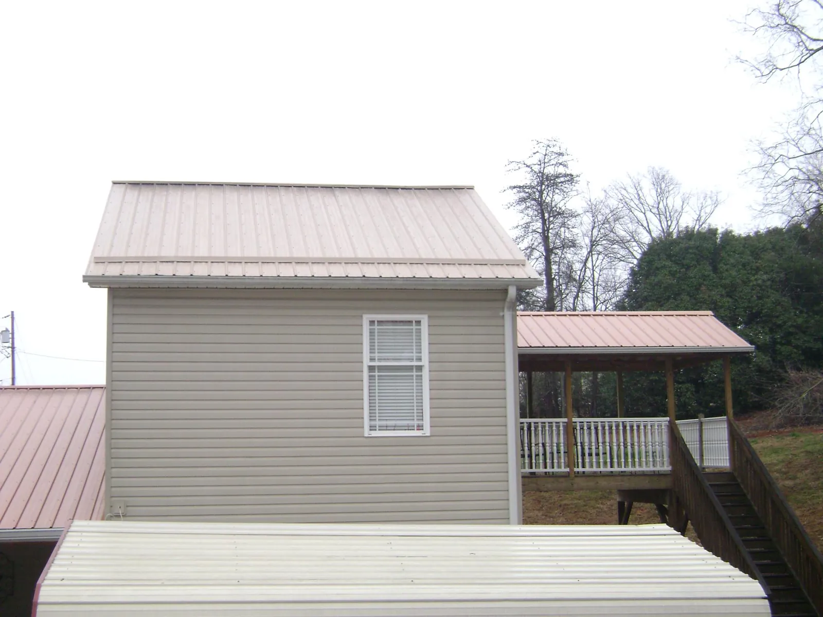 Tan metal roofs on a two story addition and attached porch, from a Roof Replacement job in Warner Springs
