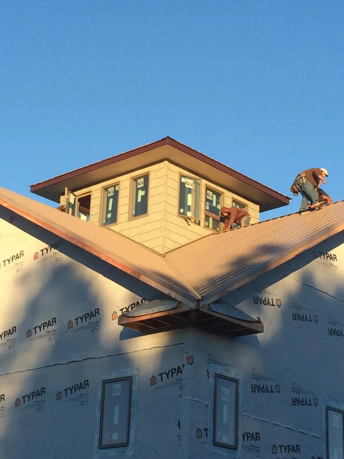 Roofers working around a rooftop cupola on a new metal roof at sunset — Roof Waterproofing in Warner Springs by Roofing Brothers
